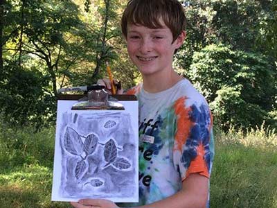 Boy holding leaf rubbing artwork