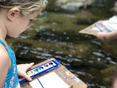 Child creating art at stream